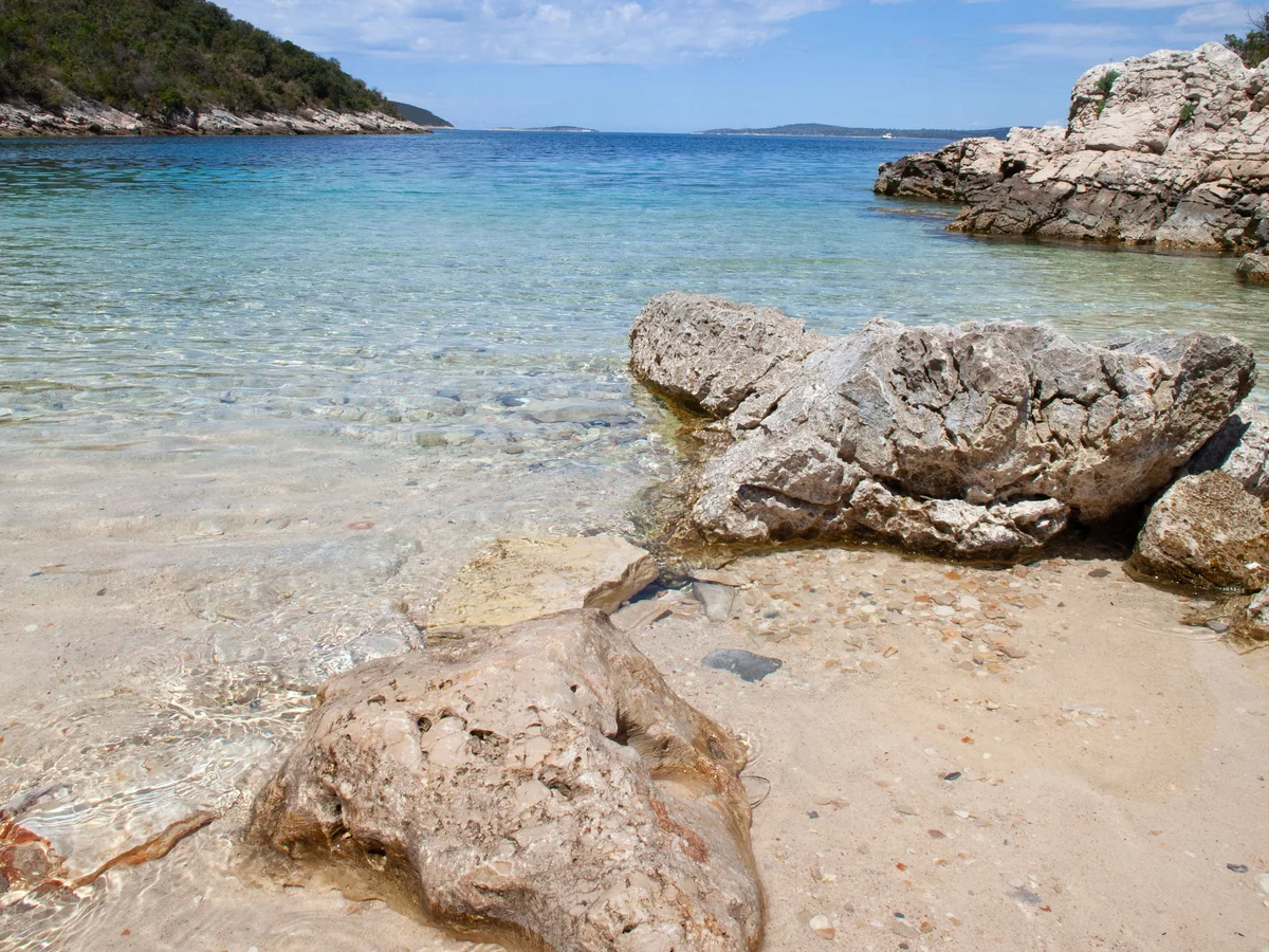 A rocky Šolta cove with clear water and another island visible on the horizon